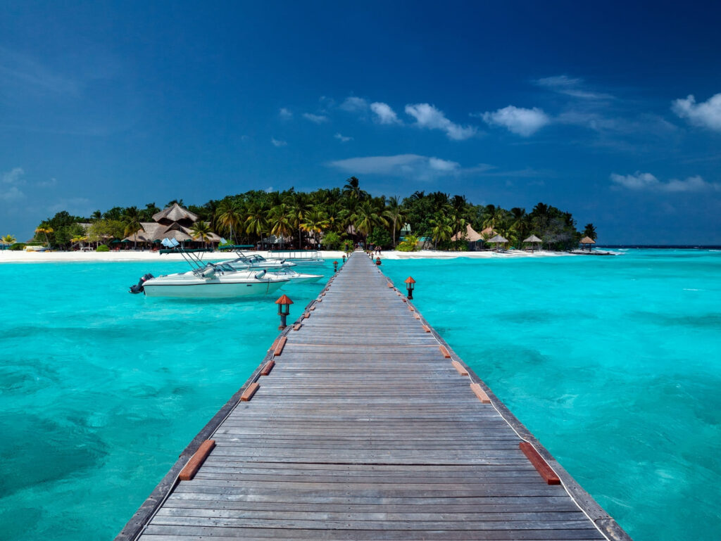 Passerella che funge da molo per un'isole delle Maldive. Il mare è azzurro cristallino