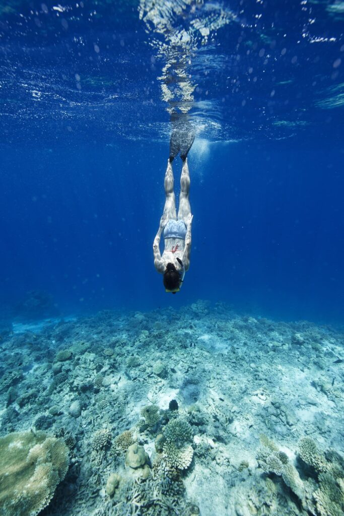 Donna che fa immersioni che nuota verso il fondale